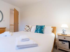 a bedroom with a white bed with towels on it at Holiday Home Marshmallow House by Interhome in St Austell