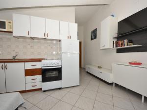 eine Küche mit weißen Schränken und einem Herd mit Backofen in der Unterkunft Apartment Mia-3 by Interhome in Obrovac