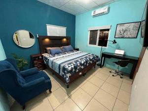 a bedroom with a bed and a chair and a mirror at Departamento Centrico, cerca de todos los balnearos de Puerto Barrios in Puerto Barrios