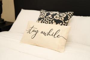 a pillow that says lay awhile on a bed at Sunset Cove Barbados in Christ Church