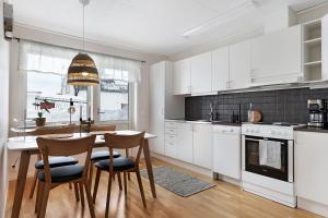 ボーデンにあるGuestly Homes - 1BR Cozy Apartmentの白いキャビネット、テーブルと椅子付きのキッチンが備わります。