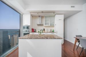 a kitchen with white cabinets and a large window at Downtown Apartments (5) in Toronto