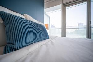 a bed with a blue and white pillow on it at Downtown Apartments (5) in Toronto
