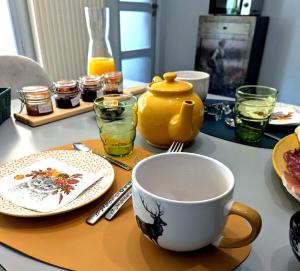 a table with a coffee cup and plates and glasses at Chez Nick et Martine suite privative in Palinges