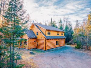 a log cabin in the middle of a forest at Serenity Private Hot Tub - Fiddler Lake in Mille-Isles