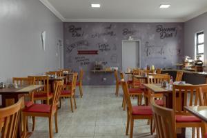 un comedor con mesas y sillas y escritura en la pared en Carlton Express Imbiara, en Araxá