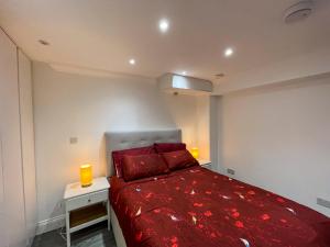 um quarto com uma cama vermelha e 2 almofadas vermelhas em 1 Bedroom Flat with whirlpool bath em Londres