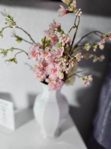 a white vase filled with pink flowers on a table at HOTEL Schiff in Rastatt