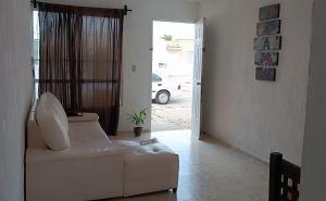 a living room with a white couch and a window at alojamiento económico in Mérida