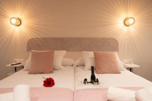 Un dormitorio con una cama blanca con una flor roja. en Boutique Rooms Playa Burriana, en Nerja