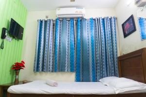 a bedroom with blue curtains and a bed in a room at Hotel Panthapath Dhaka in Dhaka