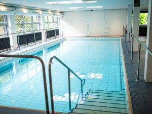 a large indoor swimming pool with stairs in a building at Apartment Gästehaus Grönebach mit Pool-3 by Interhome in Winterberg