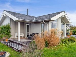 a small house with a wooden deck in the yard at Holiday Home Elja - 400m to the inlet in Sealand by Interhome in Jægerspris
