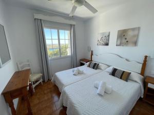 a bedroom with two beds and a table and a window at Apartamento 204 Castell Sol CB in Arenal d'en Castell