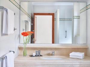 een badkamer met een wastafel en een vaas met oranje bloemen bij Apartment Hapimag-1 by Interhome in Platja  d'Aro