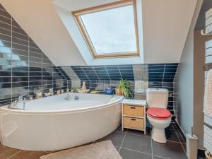 een badkamer met een bad, een toilet en een raam bij Holiday Home Villa Rucette by Interhome in La Richardais