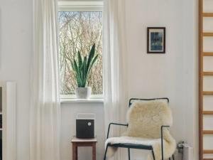 uma cadeira num quarto com uma janela em Holiday Home Birtir - 750m from the sea in NW Jutland by Interhome em Hanstholm