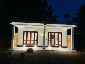 una pequeña casa blanca con puertas por la noche en Oqura Villa, en Ahangama
