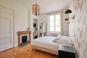 - une chambre blanche avec un lit et une cheminée dans l'établissement Maison Martouret - Colodge, à Andrézieux-Bouthéon