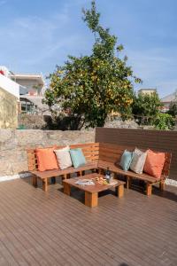 two benches with pillows and a table on a deck at Host Wise - Charming Spacious Duplex House in Infesta