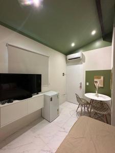 sala de estar con TV y mesa con sillas en Aconchegante Suite green, en Niterói