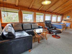 a living room with a black leather couch and a chair at Holiday Home Hunlef - 1-7km from the sea in Western Jutland by Interhome in Bolilmark