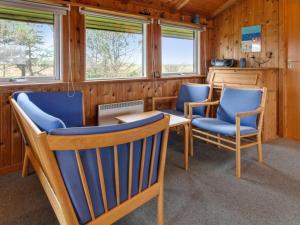 a room with blue chairs and a table and windows at Holiday Home Hunlef - 1-7km from the sea in Western Jutland by Interhome in Bolilmark