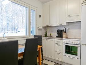 une cuisine avec des armoires blanches, une table et une fenêtre dans l'établissement Holiday Home Ylä-luosta by Interhome, à Rautavaara 5 autres photos