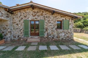 a stone house with green shutters on it at Apartments La Tenuta where the sea meets the land - Goelba in Porto Azzurro