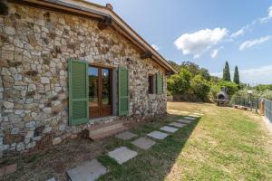 a stone house with green shutters and a yard at Apartments La Tenuta where the sea meets the land - Goelba in Porto Azzurro
