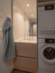 a bathroom with a washing machine and a sink at Wohntraum direkt am See in Stansstad