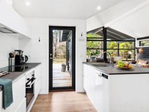 uma cozinha com armários brancos e uma porta que leva a um pátio em Holiday Home Ela - 800m from the sea in Sealand by Interhome em Vig