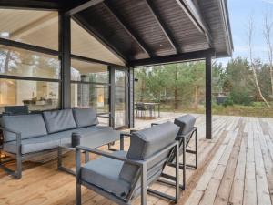 a screened in porch with chairs and a couch at Holiday Home Ela - 800m from the sea in Sealand by Interhome in Vig