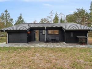 uma pequena casa preta com um pátio em Holiday Home Ela - 800m from the sea in Sealand by Interhome em Vig