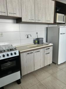 a kitchen with a sink and a stove and refrigerator at Loft Central in Passo Fundo