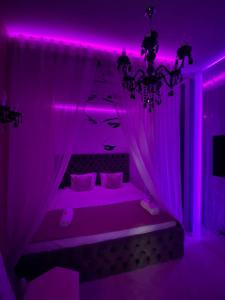 Un dormitorio con iluminación púrpura y una cama con una mujer en Mystik Penthouse, en Sighişoara