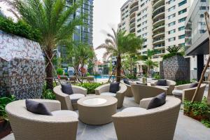 d'une terrasse avec des chaises, des tables et des palmiers. dans l'établissement LUMIÈRE RESIDENT LUXURY SUITE, à Hô-Chi-Minh-Ville