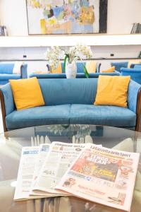 ein Wohnzimmer mit einem Sofa und einem Tisch mit einer Zeitung in der Unterkunft Melas Hotel in Merate