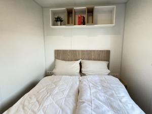 un letto con lenzuola e cuscini bianchi in una stanza di Holiday Home Tiny Haus Libelle by Interhome a Riedenburg