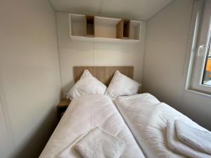 a small bedroom with a bed with white sheets and pillows at Holiday Home Tiny Haus Libelle by Interhome in Riedenburg
