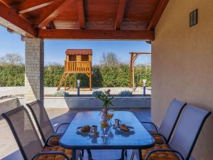 a table and chairs on a patio with a playground at Apartment Emili by Interhome in Vižinada