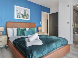 ein blaues Schlafzimmer mit einem Bett mit Handtüchern darauf in der Unterkunft Apartment North Acton-2 by Interhome in London