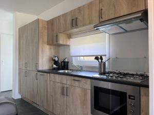 a kitchen with wooden cabinets and a stove top oven at Holiday Home De Noordzee by Interhome in Scherpenisse