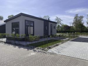 a small house with a fence in front of it at Holiday Home De Noordzee by Interhome in Scherpenisse