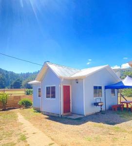 una pequeña casa blanca con una puerta roja y una mesa de picnic en Cabañas Pudá en Dichato