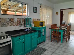 a kitchen with green cabinets and a table with a microwave at Casita verde in Garopaba