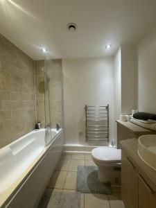 a bathroom with a tub and a toilet and a sink at Modern Apartment in City Centre in Manchester
