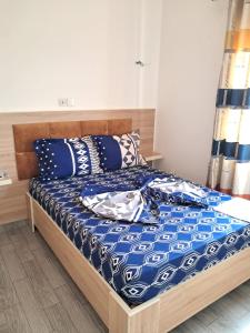 een bed met blauwe en witte lakens en kussens bij Residence New Standing Douala CITE CHIRAC YASSA in Douala