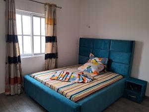 Cama azul en habitación con ventana en Residence New Standing Douala CITE CHIRAC YASSA, en Douala