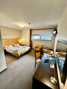 オストルフ・ビエルコポルスキにあるHotel Pod Dębamiのベッドとデスクが備わるホテルルームです。